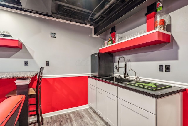 kitchen with white cabinetry, sink, and light hardwood / wood-style flooring