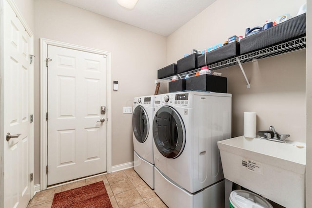 laundry area with light tile patterned floors, separate washer and dryer, and sink