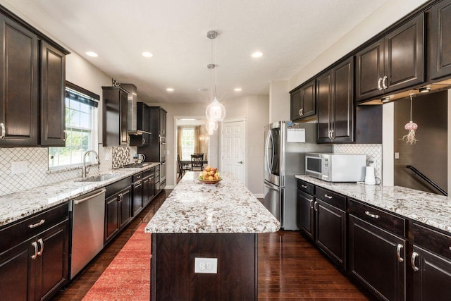 kitchen with dark hardwood / wood-style flooring, stainless steel appliances, sink, decorative light fixtures, and a kitchen island