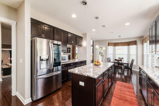 kitchen featuring decorative light fixtures, dark brown cabinetry, stainless steel appliances, and a kitchen island