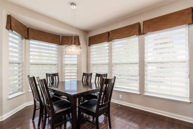 dining space with dark hardwood / wood-style floors and a notable chandelier