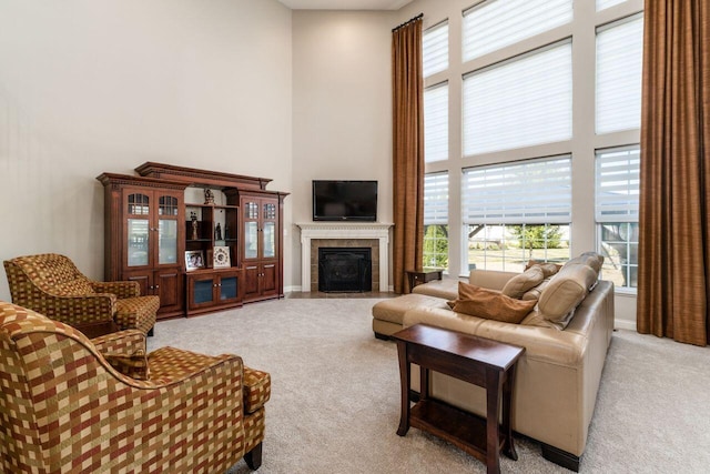 carpeted living room featuring a towering ceiling and a tiled fireplace