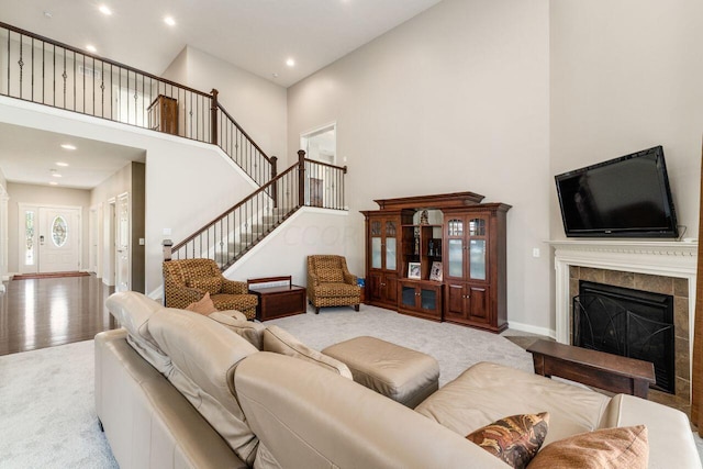 carpeted living room with a towering ceiling and a tiled fireplace