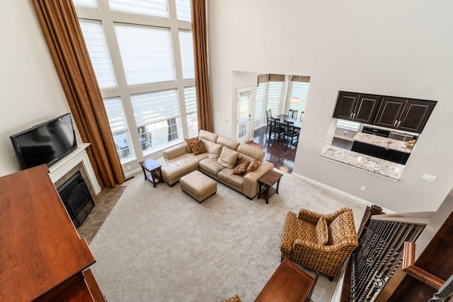 living room with a towering ceiling, a fireplace, and light carpet