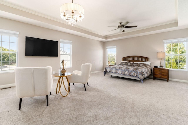 bedroom featuring a tray ceiling, multiple windows, and ceiling fan with notable chandelier