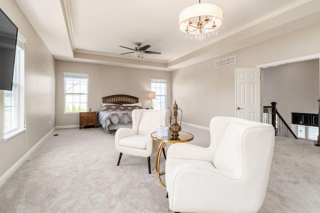 carpeted bedroom featuring ceiling fan with notable chandelier, ornamental molding, multiple windows, and a tray ceiling