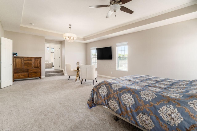 carpeted bedroom featuring ceiling fan with notable chandelier, ornamental molding, and a tray ceiling