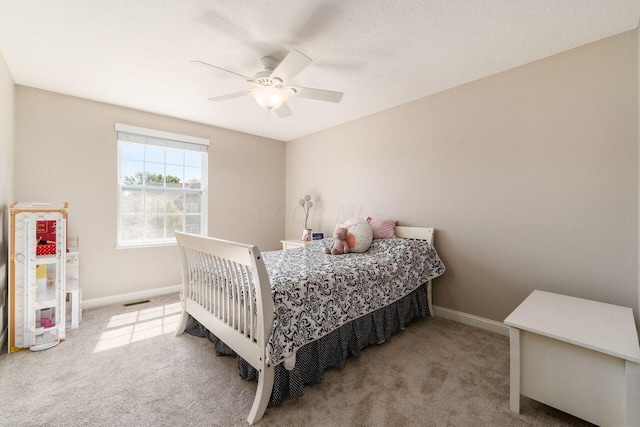 bedroom featuring light carpet, a textured ceiling, and ceiling fan