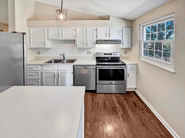 kitchen with white cabinets, sink, vaulted ceiling, decorative light fixtures, and stainless steel appliances