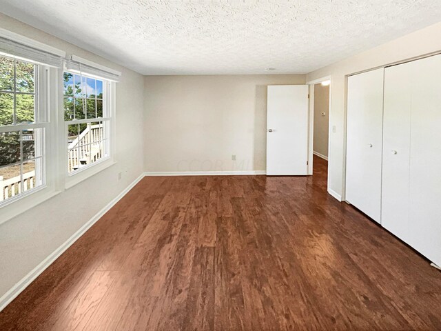 unfurnished bedroom with a textured ceiling, a closet, and dark hardwood / wood-style floors