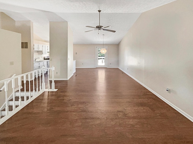 unfurnished room with a textured ceiling, ceiling fan, dark hardwood / wood-style flooring, and vaulted ceiling