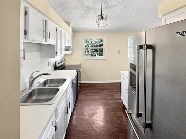 kitchen featuring sink, dark hardwood / wood-style floors, appliances with stainless steel finishes, decorative light fixtures, and white cabinetry