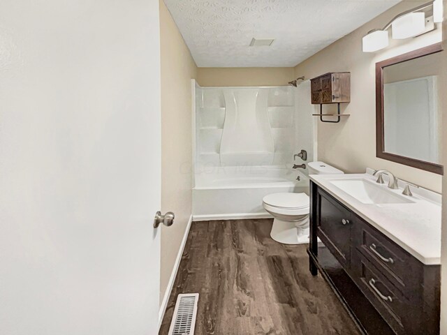 full bathroom featuring hardwood / wood-style floors, vanity, bathtub / shower combination, toilet, and a textured ceiling