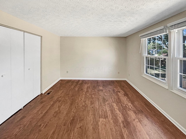 unfurnished bedroom featuring hardwood / wood-style floors, a textured ceiling, and a closet