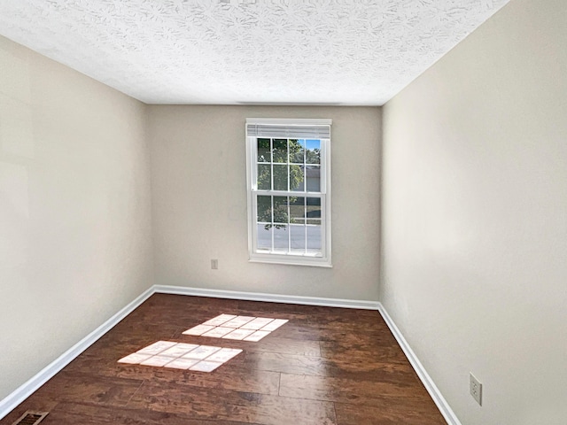 empty room featuring a textured ceiling and dark hardwood / wood-style floors