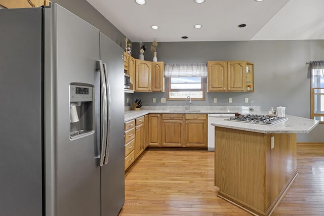 kitchen with sink, light stone counters, light hardwood / wood-style floors, light brown cabinetry, and appliances with stainless steel finishes