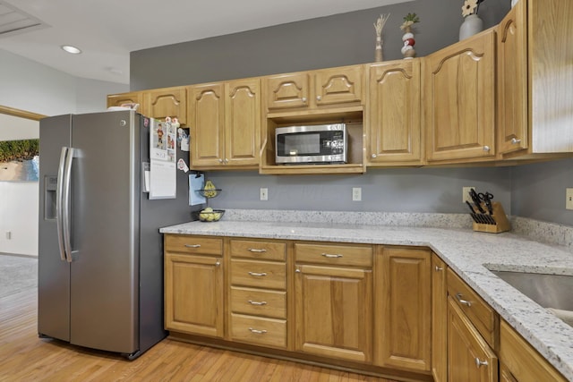 kitchen with light stone counters, sink, light wood-type flooring, and appliances with stainless steel finishes