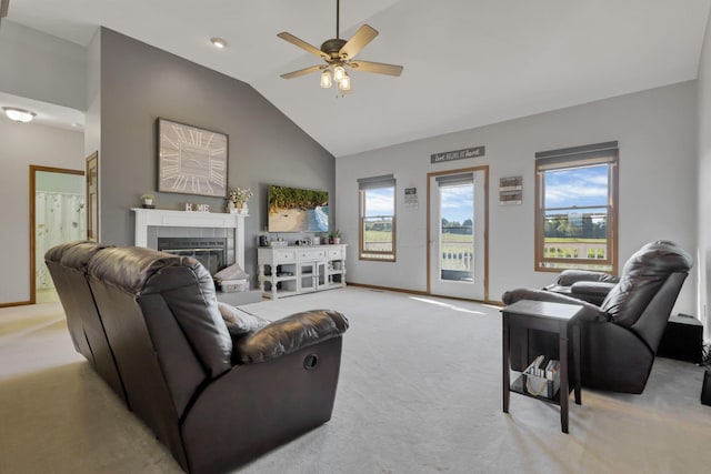 carpeted living room with a tiled fireplace, ceiling fan, and high vaulted ceiling