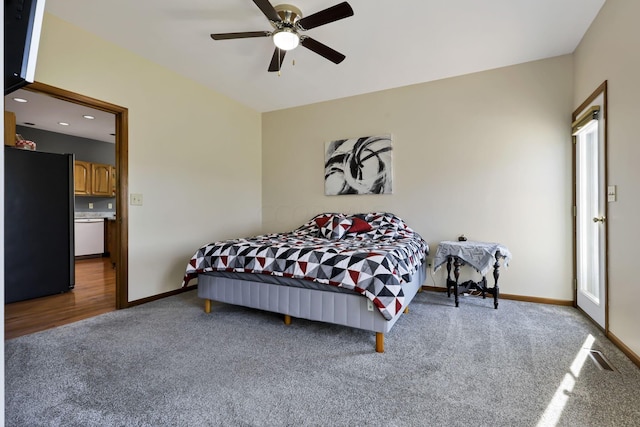 carpeted bedroom featuring multiple windows, ceiling fan, and black refrigerator