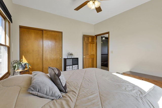 bedroom with multiple windows, ceiling fan, and a closet