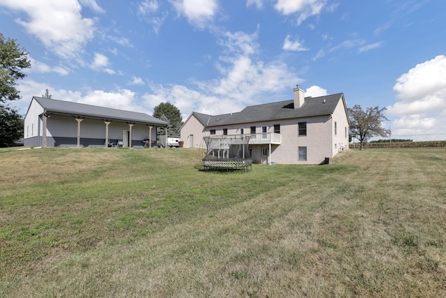 rear view of house with a trampoline and a yard