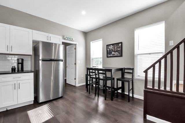 kitchen with white cabinets, stainless steel fridge, dark hardwood / wood-style flooring, and backsplash