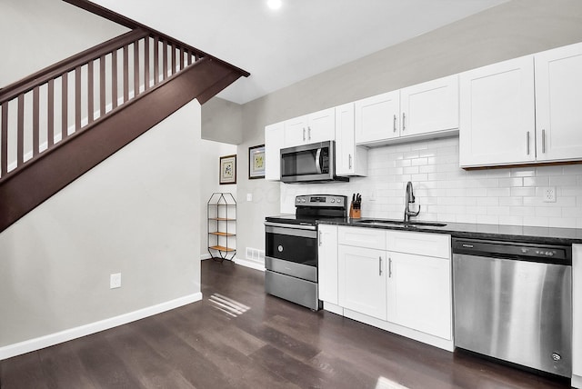 kitchen featuring stainless steel appliances, white cabinetry, dark wood-type flooring, and sink