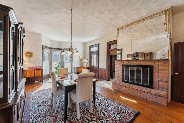 dining space with a fireplace, hardwood / wood-style floors, and an inviting chandelier