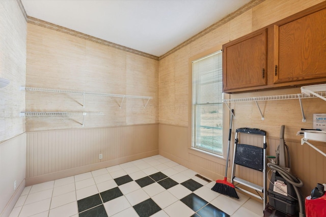 clothes washing area with wood walls, cabinets, and light tile patterned floors