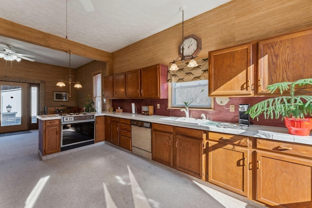 kitchen with light carpet, stainless steel appliances, sink, tile countertops, and decorative light fixtures