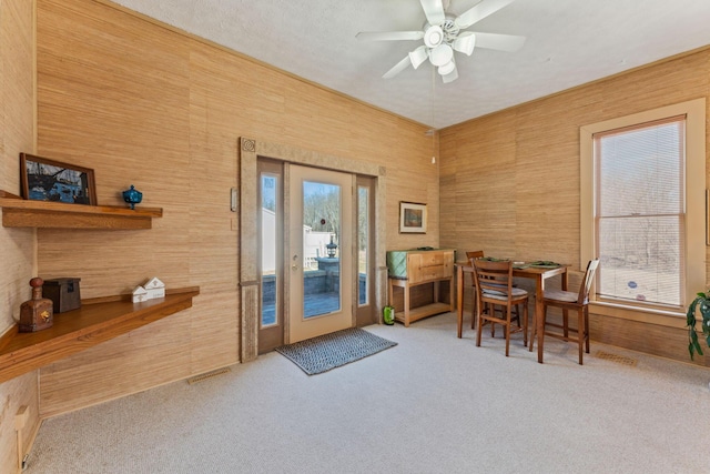 doorway with ceiling fan, french doors, carpet, and wood walls