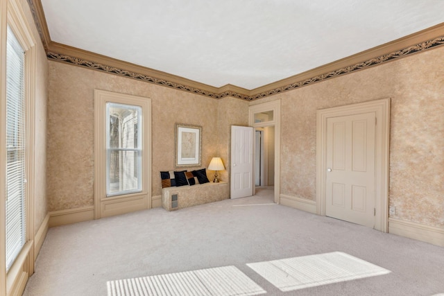 unfurnished living room with ornamental molding, light colored carpet, and a healthy amount of sunlight