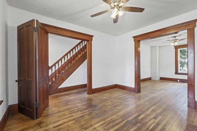 spare room featuring a textured ceiling, ceiling fan, and dark wood-type flooring