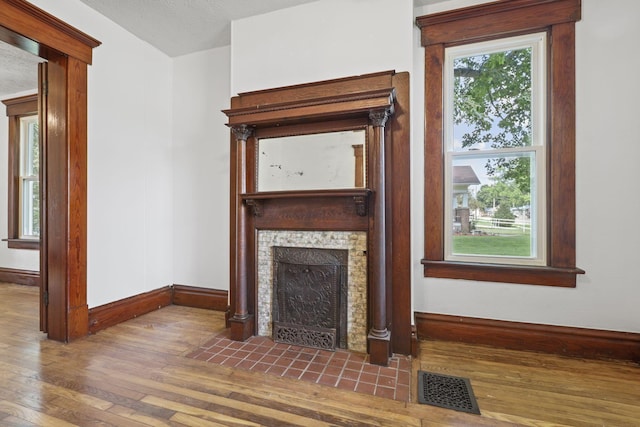 unfurnished living room with hardwood / wood-style floors, a textured ceiling, and a tile fireplace