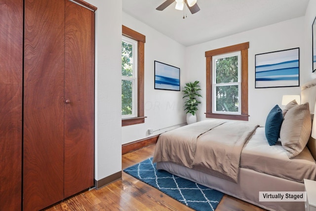 bedroom with hardwood / wood-style flooring, ceiling fan, and multiple windows