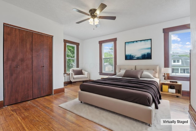 bedroom featuring a closet, ceiling fan, light hardwood / wood-style flooring, and a textured ceiling