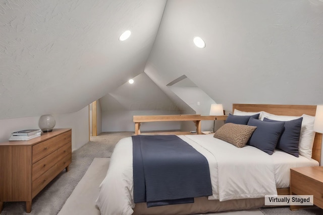 bedroom featuring a textured ceiling, light carpet, and lofted ceiling