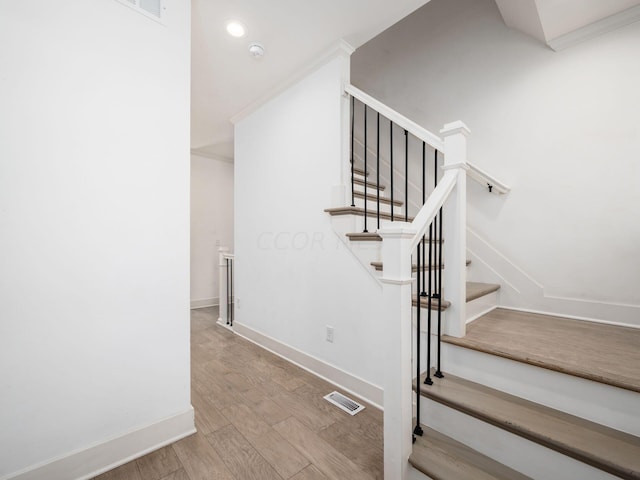 stairs with crown molding and hardwood / wood-style flooring