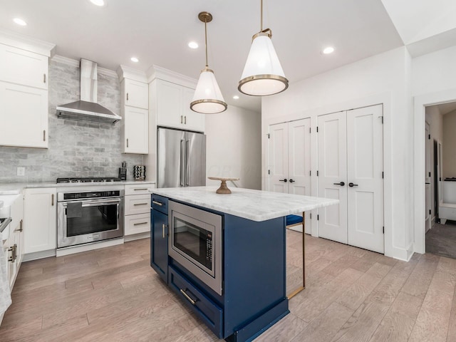 kitchen featuring wall chimney exhaust hood, a center island, white cabinetry, and stainless steel appliances