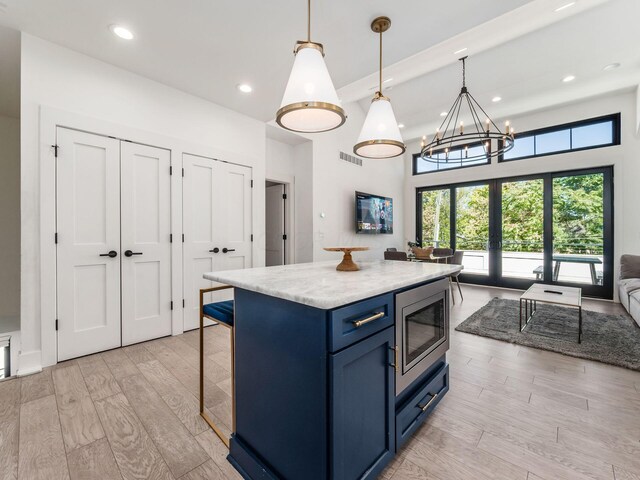 kitchen with french doors, light hardwood / wood-style flooring, hanging light fixtures, a center island, and stainless steel microwave