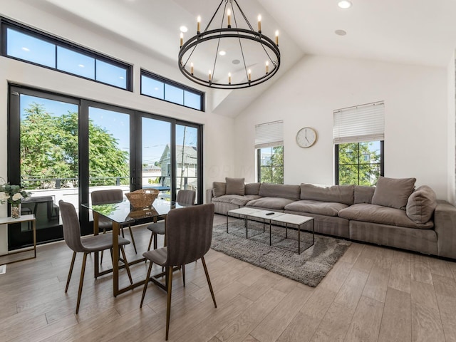 dining area with high vaulted ceiling, a chandelier, and light hardwood / wood-style floors