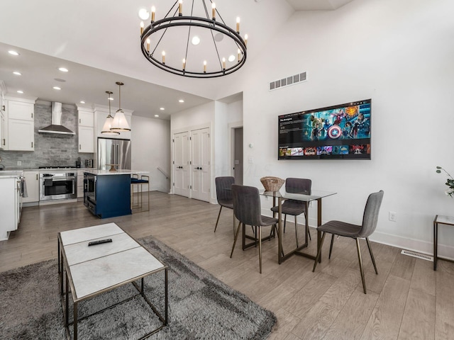 dining area with light hardwood / wood-style flooring, high vaulted ceiling, and a chandelier