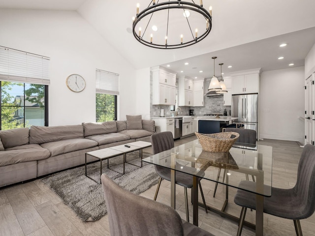 living room featuring a notable chandelier, high vaulted ceiling, and light hardwood / wood-style flooring