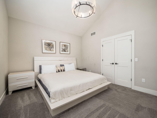 bedroom with dark colored carpet, high vaulted ceiling, and a closet