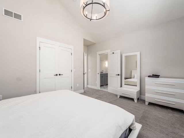 carpeted bedroom with ensuite bath, sink, an inviting chandelier, high vaulted ceiling, and a closet