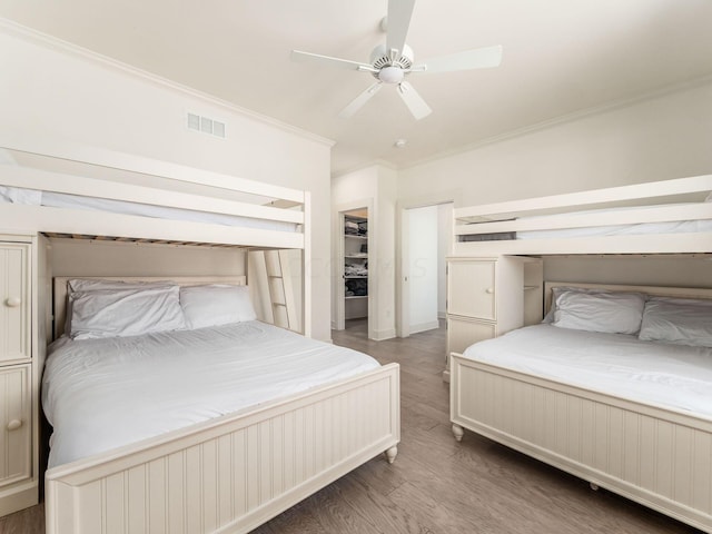 bedroom with a closet, dark hardwood / wood-style floors, ceiling fan, and ornamental molding