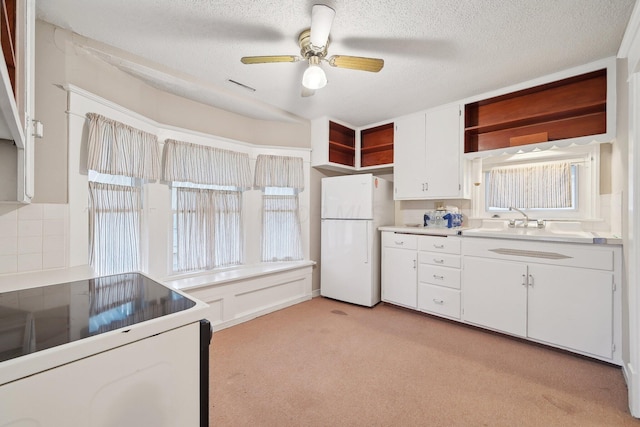 kitchen featuring white cabinets, stove, white fridge, and a wealth of natural light