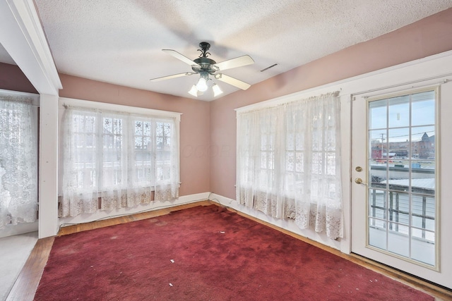 interior space with ceiling fan, a textured ceiling, and a wealth of natural light