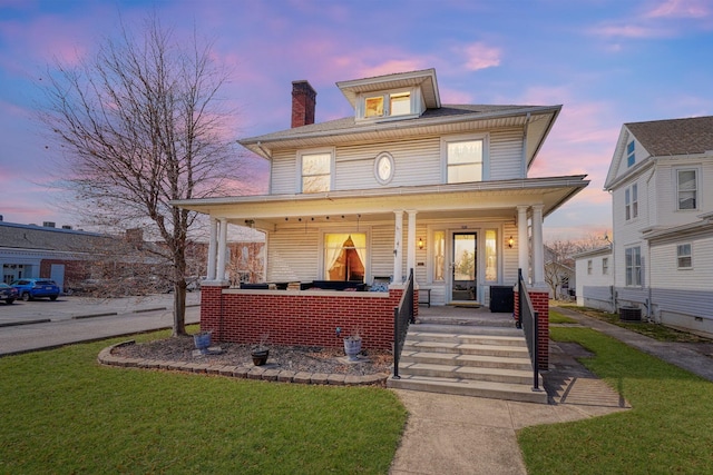 traditional style home with central AC unit, a lawn, a porch, and a chimney