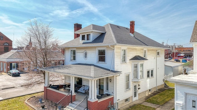 view of front of property featuring a shingled roof and a chimney